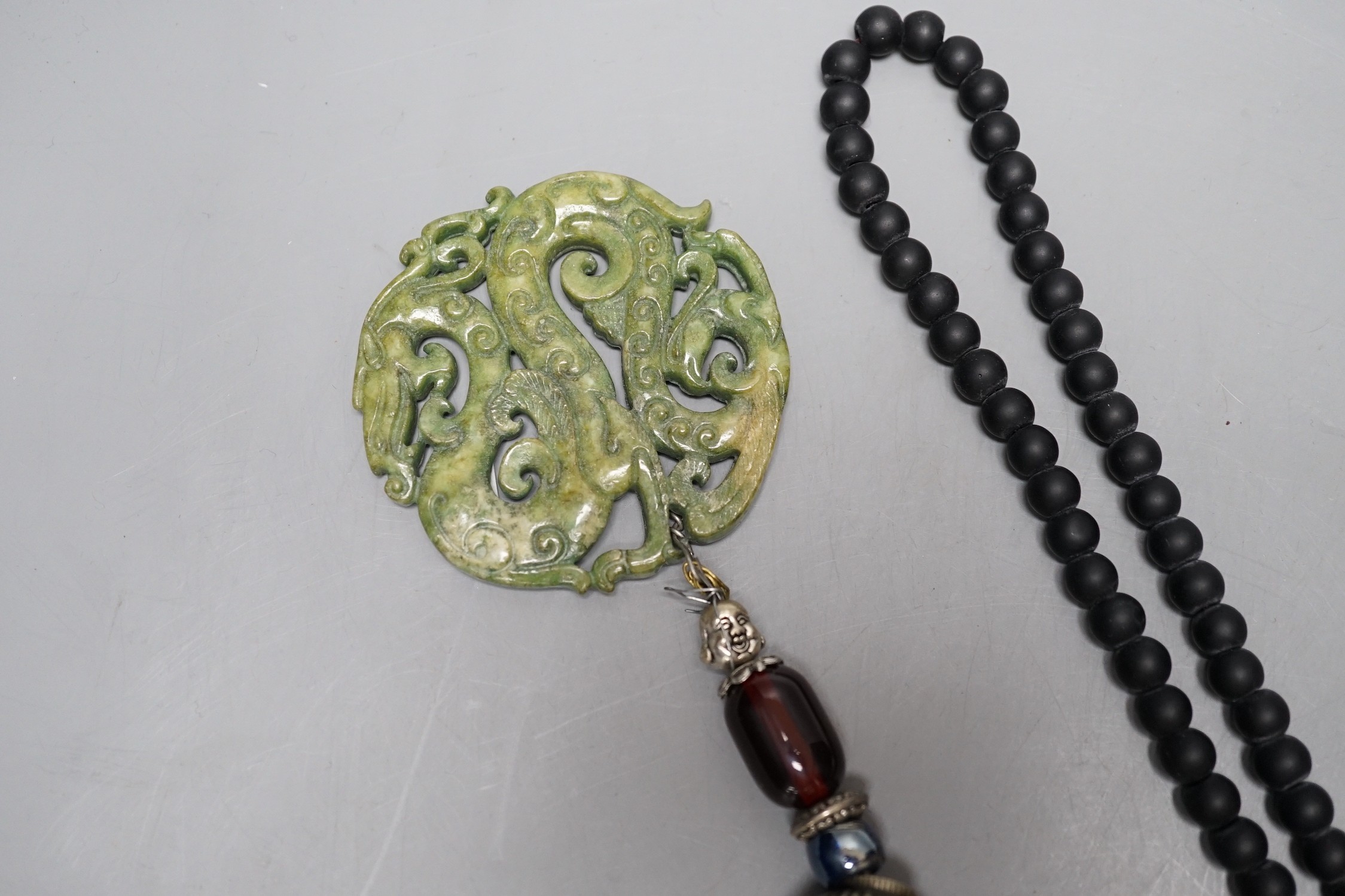 Four Chinese jade or hardstone pendants, one on bead necklace, the other on tassle